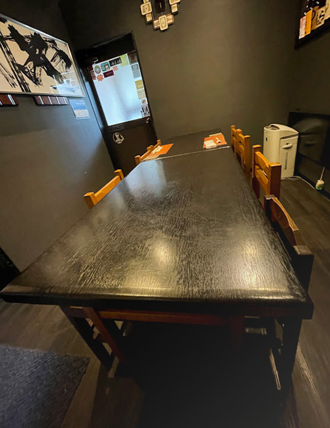 ８人分入る余裕のある部屋に置かれた長方形の黒い机