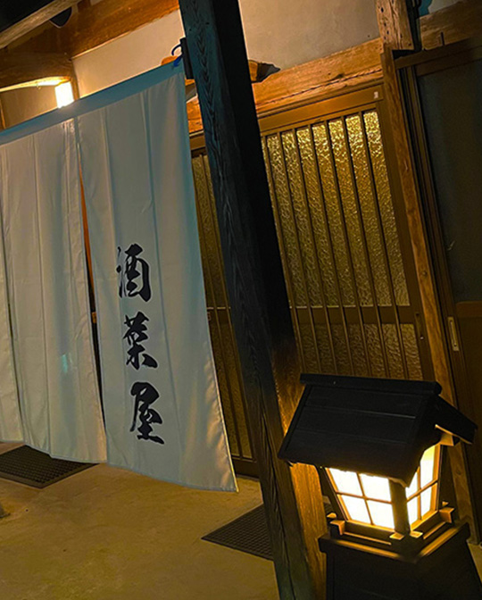 斜めから撮影された明かりが灯る酒奈屋の玄関